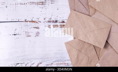 Pile of Brown Kraft Envelopes on Rustic White Wooden Background with Copy Space Stock Photo