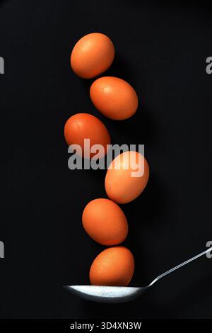 six brown eggs in a vertical  column with large spoon underneath Stock Photo