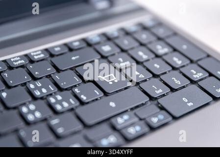Close-up of laptop keyboard with shopping cart icon key, concept of online shopping, e-commerce, payment, and digital retail business technology Stock Photo