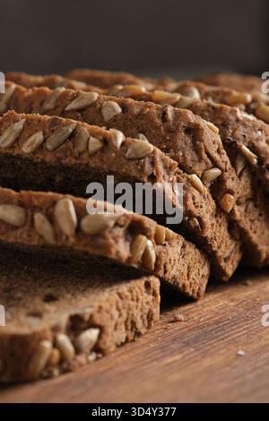 Slices of brown bread with sunflower seeds on wooden table Stock Photo