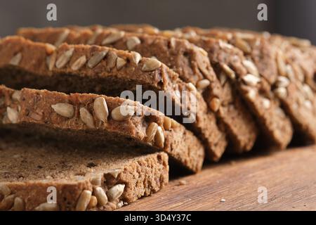Sliced rye bread with sunflower seeds on wooden board, closeup Stock Photo