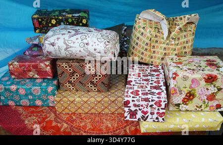 Stacks of gifts wrapped in batik-patterned paper were presented by the guests to the host who was celebrating a moment of happiness in his life Stock Photo