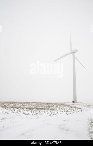 View of a solitary wind turbine stands tall against the stark, snow-laden landscape, a beacon of clean energy in the wintry expanse, Syracuse, New Yor Stock Photo