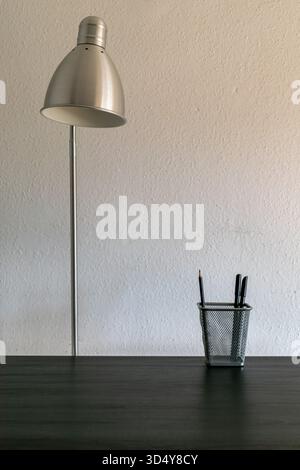 Desk lamp and pencil holder on a wooden table in home office Stock Photo