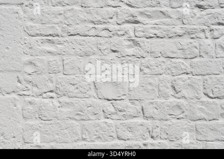 Close-up view of whitewashed brick wall, rough texture and irregularities of bricks. Surface highlights natural rustic character of stonework, commonl Stock Photo