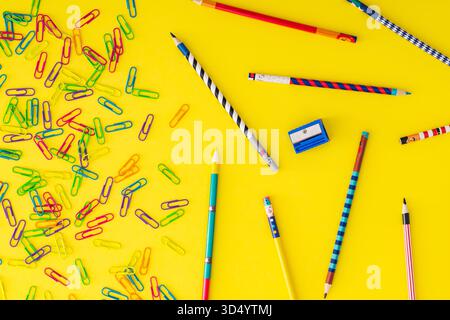 Colorful back to school composition with paper clips and  coloured pencils on yellow background. Learning and creativity concept. Stock Photo
