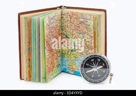 Vintage geographical maps in open atlas book with compass on white background isolated. Adventure and travel concept. Classic tools for orientation in Stock Photo