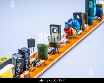 Macro shot of an orange printed circuit board (PCB) with various electronic components. Stock Photo