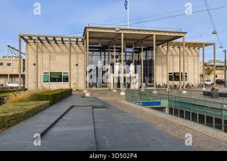 The Brutalist architecture of Zutphen train station in the Netherlands, featuring a prominent concrete canopy, glass facade, and a wide public plaza. Stock Photo