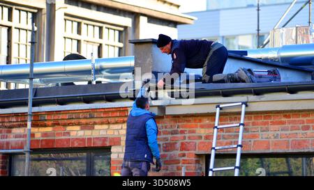 Warsaw, Poland. 6 November 2025. Two workers are repairing the roof Stock Photo