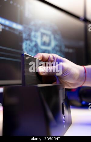 Close up of hacker using SSD to store data gathered from victims using spyware installed on their systems. Evil man inserting hard drive containing exploit used to gain unauthorized access Stock Photo