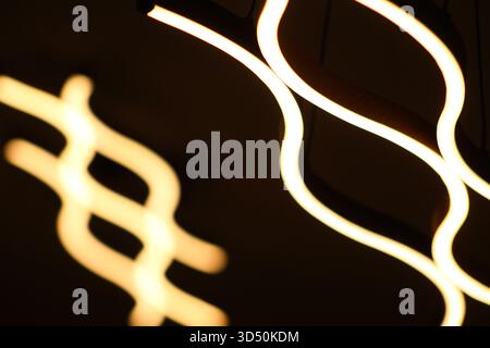Artistic photo showing glowing curved LED lines forming an abstract shape, symbolizing innovation and modern interior design. Stock Photo