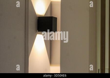 Contemporary interior design featuring vertical wooden slat panels illuminated by two ceiling spotlights, creating a warm and stylish atmosphere. Stock Photo