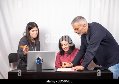 Brainstorming between three colleagues. The two women and the man are about forty years old and are of Italian origin Stock Photo
