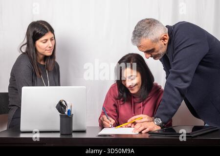 Brainstorming between three colleagues. The two women and the man are about forty years old and are of Italian origin Stock Photo