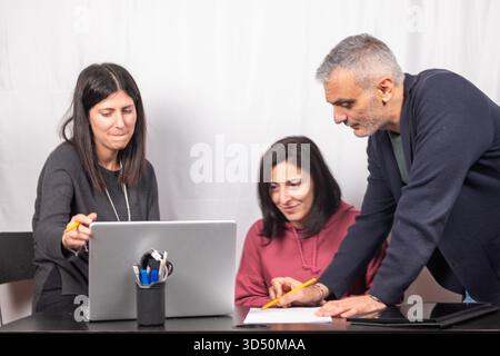 Brainstorming between three colleagues. The two women and the man are about forty years old and are of Italian origin Stock Photo