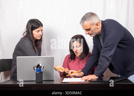 Brainstorming between three colleagues. The two women and the man are about forty years old and are of Italian origin Stock Photo