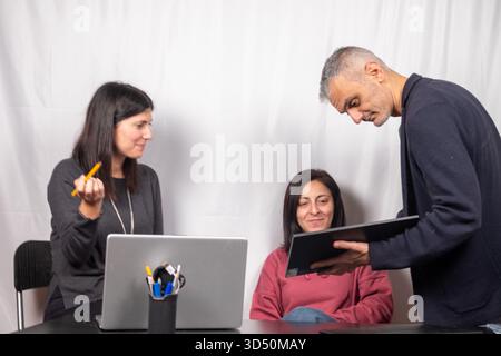 Brainstorming between three colleagues. The two women and the man are about forty years old and are of Italian origin Stock Photo