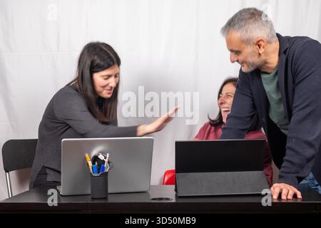 Brainstorming between three colleagues. The two women and the man are about forty years old and are of Italian origin Stock Photo