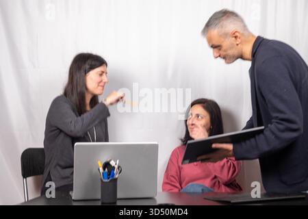 Brainstorming between three colleagues. The two women and the man are about forty years old and are of Italian origin Stock Photo