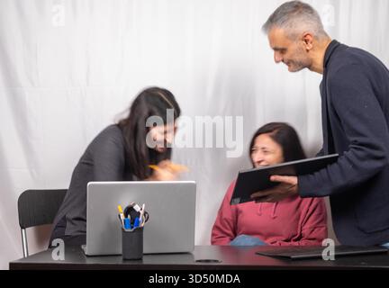 Brainstorming between three colleagues. The two women and the man are about forty years old and are of Italian origin Stock Photo