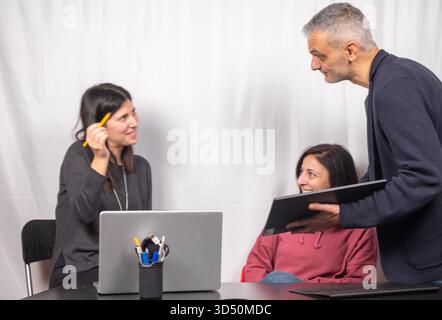 Brainstorming between three colleagues. The two women and the man are about forty years old and are of Italian origin Stock Photo
