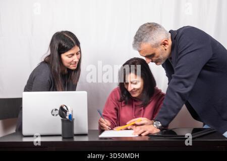 Brainstorming between three colleagues. The two women and the man are about forty years old and are of Italian origin Stock Photo