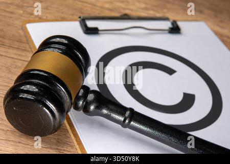Close-up of a judge's gavel placed beside a copyright symbol on a clipboard. Intellectual property law, copyright protection, and legal rights Stock Photo
