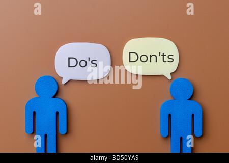 Two blue figures with speech bubbles discussing Do's and Don'ts. Rules, guidelines, right versus wrong, and business compliance or advice concept. Stock Photo
