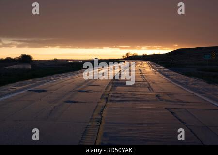 Moody stretch of wet highway pavement after a storm at sunset on the high plains of America Stock Photo