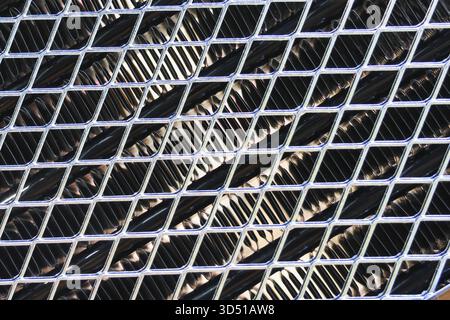Industrial metal mesh grille with geometric diamond pattern. strong abstract background texture over powerful radiator, engine or machine part for coo Stock Photo