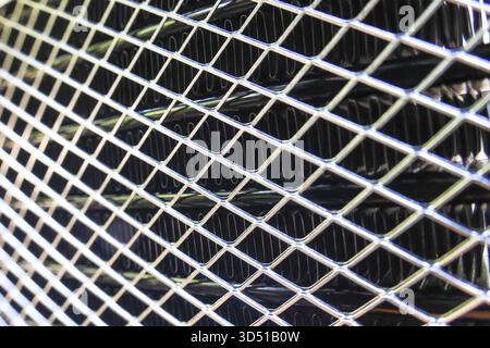 Close up of silver metal grate with diamond pattern. This industrial texture creates strong, protective feeling with its repetitive geometric design a Stock Photo
