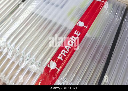 Close up view of red fragile warning tape on parcel. Protective air bubble packaging material for secure shipping and careful delivery, ensuring safet Stock Photo