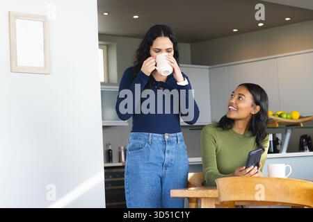 Diverse female colleagues standing at kitchen island reviewing ...