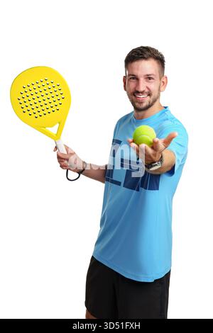 Young man holds paddle and ball, ready to play paddle tennis in bright studio setting Stock Photo