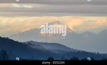 mountain peak with snow and mist under dramatic clouds Stock Photo