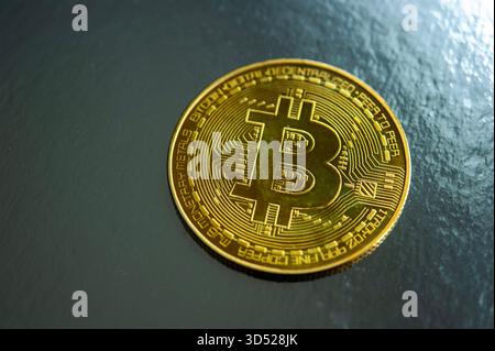 Gold Bitcoin coin on dark textured surface symbolizing cryptocurrency and digital finance Stock Photo