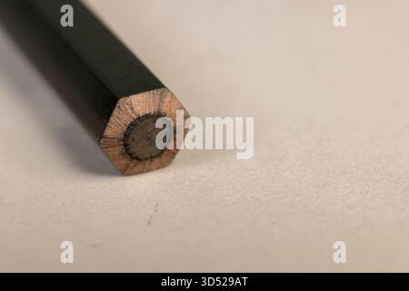 a row of black wooden pencils folded on cheap loose paper, wooden pencils with graphite lead for drawing Stock Photo