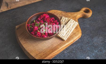 Freshly mixed homemade vinaigrette arranged in a handcrafted clay bowl with crunchy grain crackers placed nearby on a kitchen table. A calm domestic e Stock Photo