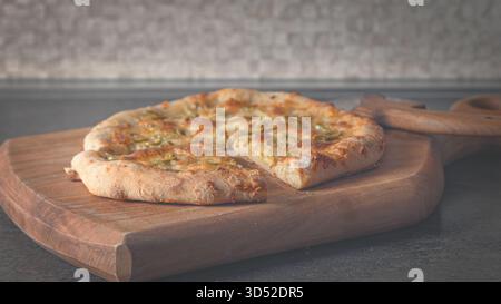 Warm cheesy pizza with herbs, fresh from the oven, displayed on a textured wooden cutting board Stock Photo