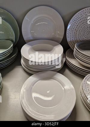 Stacked ceramic plates in neutral colors displayed on a shelf. Simple and elegant design with clean lines and minimal patterns. Stock Photo