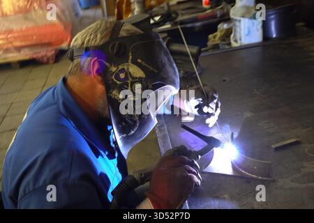 Moscow, Russia - June 3, 2018: Welder welds metal parts on a workbench. Stock Photo