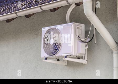 Inverter split system, heating and cooling pump installed under roof of family home Stock Photo