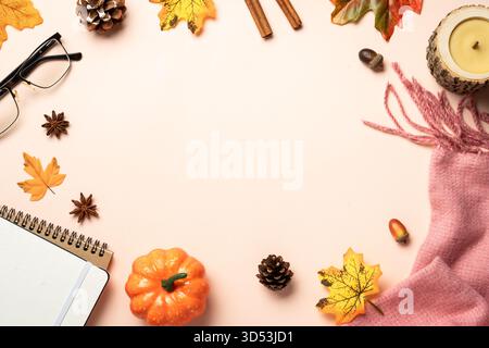 Autumn flat lay background. Autumn leaves, notepad, scarf, candle and spices on yellow background. Stock Photo
