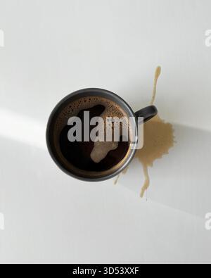 Overhead view of a cup of black coffee spilled on a  white table Stock Photo