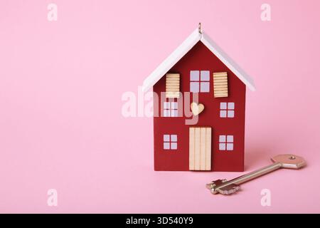 Wooden house model with key on pink background. Top view Stock Photo