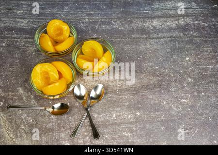 Half-cut peaches, canned preserve. Close-up photograph with copy space on a rustic background. Stock Photo