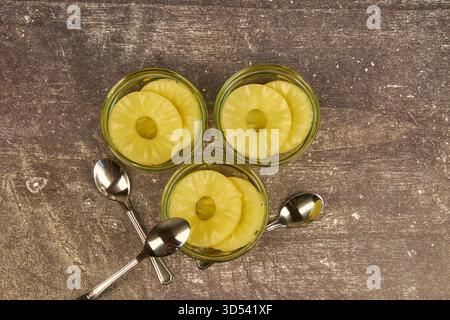 Sliced ​​pineapple, canned preserve. Close-up photograph with copy space on a table against a rustic background. Stock Photo