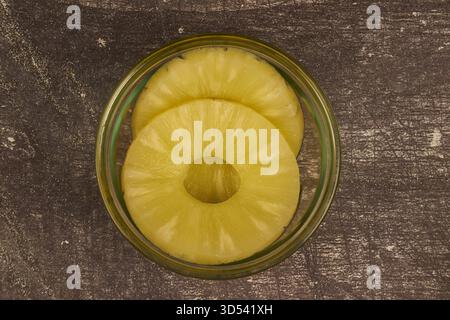Sliced ​​pineapple, canned preserve. Close-up photograph with copy space on a table against a rustic background. Stock Photo