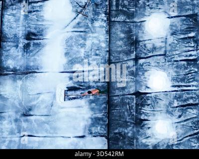 Aerial view of a person on a dark blue patterned surface, possibly a wall or floor, with white accents and light spots, Ninh Hoa, Khanh Hoa, Vietnam. Stock Photo